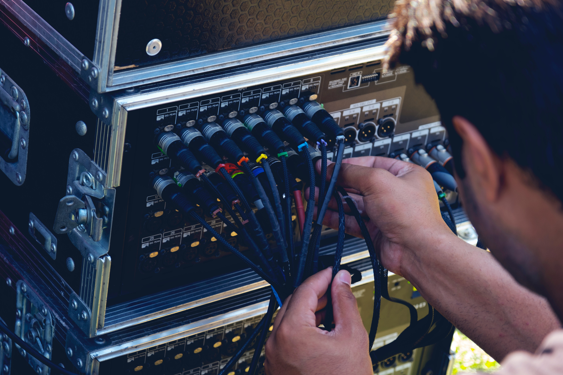 Sound engineer plugging audio cable on studio system boxes.